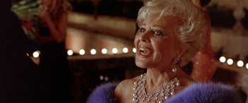 Movie still from “Any Given Sunday” (1999), directed by Oliver Stone – An older woman wearing pearls and a purple dress; Close Up shot, Low angle
