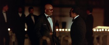 Movie still from “Any Given Sunday” (1999), directed by Oliver Stone – Two men in tuxedos talking to each other in front of candles; Medium shot, Low angle