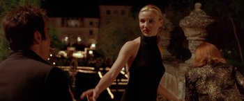 Movie still from “Any Given Sunday” (1999), directed by Oliver Stone – A woman in a black dress standing in front of a building; Medium shot, Over the shoulder angle