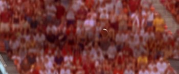 Movie still from “Any Given Sunday” (1999), directed by Oliver Stone – A crowd of people in a stadium watching a ball fly through the air; Extreme Close Up shot, Low angle