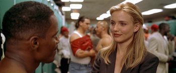 Movie still from “Any Given Sunday” (1999), directed by Oliver Stone – A woman standing next to a crowd of people in a room; Close Up shot, Over the shoulder angle
