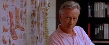 Movie still from “Any Given Sunday” (1999), directed by Oliver Stone – A man standing in front of an anatomy chart; Close Up shot, Low angle