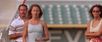 Movie still from “Any Given Sunday” (1999), directed by Oliver Stone – A woman in a white tank top holding a tennis racquet; Medium shot, Low angle