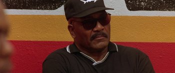 Movie still from “Any Given Sunday” (1999), directed by Oliver Stone – An older man wearing sunglasses and a baseball cap; Close Up shot, Low angle