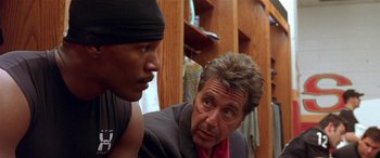 Movie still from “Any Given Sunday” (1999), directed by Oliver Stone – A man talking to another man in front of a wooden wall; Close Up shot, Over the shoulder angle
