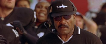 Movie still from “Any Given Sunday” (1999), directed by Oliver Stone – A man wearing a black hat and headphones; Close Up shot, Low angle
