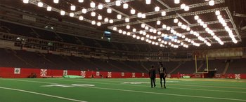 Movie still from “Any Given Sunday” (1999), directed by Oliver Stone – Two people are standing on a football field in an empty stadium; Extreme Wide shot, High angle