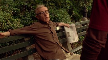 Movie still from “Anything Else” (2003), directed by Woody Allen – An older man sitting on a park bench reading a newspaper; Medium shot, Over the shoulder angle