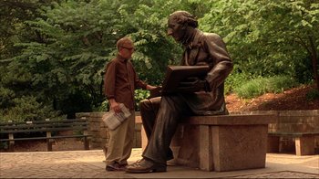 Movie still from “Anything Else” (2003), directed by Woody Allen – A man standing next to a bronze statue of a man reading; Wide shot, Low angle
