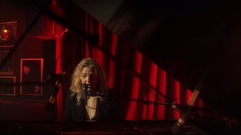 Movie still from “Anything Else” (2003), directed by Woody Allen – A woman sitting in front of a microphone in front of a red curtain; Medium shot, Low angle
