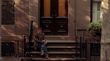 Movie still from “Anything Else” (2003), directed by Woody Allen – A man sitting on the steps of a building; Wide shot, Low angle