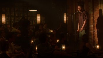 Movie still from “Anything Else” (2003), directed by Woody Allen – A group of people sitting in a room with a microphone; Wide shot, Over the shoulder angle