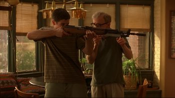 Movie still from “Anything Else” (2003), directed by Woody Allen – A man and a young boy are holding a rifle; Medium shot, Over the shoulder angle