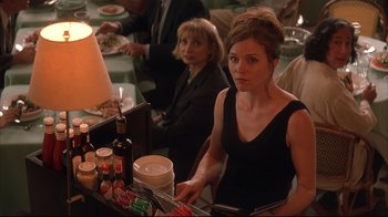 Movie still from “Anything Else” (2003), directed by Woody Allen – A woman in a black dress is standing in front of a buffet; Medium shot, Over the shoulder angle