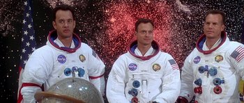 Movie still from “Apollo 13” (1995), directed by Ron Howard – Two men in space suits are standing in front of an exploding background; Medium shot, Low angle