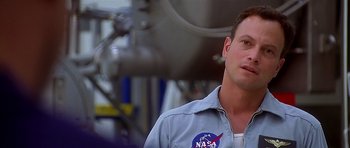 Movie still from “Apollo 13” (1995), directed by Ron Howard – A man wearing a nasa shirt standing in front of a machine; Close Up shot, Over the shoulder angle