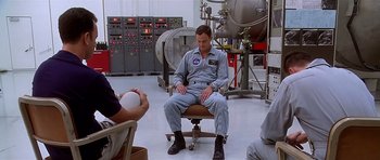 Movie still from “Apollo 13” (1995), directed by Ron Howard – A man sitting on a chair in a room; Medium shot, High angle