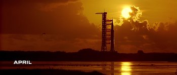 The sun is setting behind a rocket on the ground