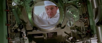 Movie still from “Apollo 13” (1995), directed by Ron Howard – A man wearing a chef's hat looking through a porthole; Medium shot, Low angle