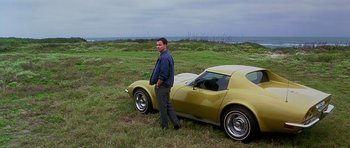 Movie still from “Apollo 13” (1995), directed by Ron Howard – A man standing next to a yellow car in a grassy field; Wide shot, Low angle