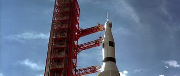 Movie still from “Apollo 13” (1995), directed by Ron Howard – A red and white rocket is in front of a red tower; Extreme Wide shot, Low angle