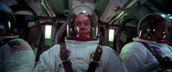 Movie still from “Apollo 13” (1995), directed by Ron Howard – A man in a spacesuit and helmet in a space ship; Medium shot, Overhead angle