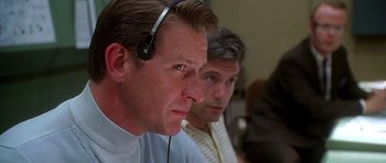 Movie still from “Apollo 13” (1995), directed by Ron Howard – A man with a headset is sitting next to another man; Close Up shot, Low angle