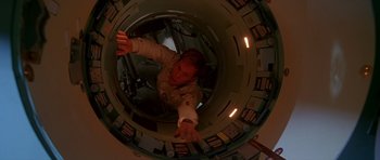 Movie still from “Apollo 13” (1995), directed by Ron Howard – A person in a space suit is inside of a space ship; Medium shot, Overhead angle