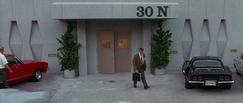 Movie still from “Apollo 13” (1995), directed by Ron Howard – A man in a suit and tie walking in front of a building; Wide shot, High angle