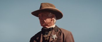 Movie still from “Appaloosa” (2008), directed by Ed Harris – An older man wearing a hat and a suit; Close Up shot, Low angle