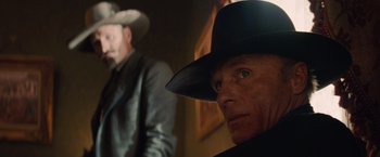 Movie still from “Appaloosa” (2008), directed by Ed Harris – A man in a black hat and a man in a black suit; Close Up shot, Low angle