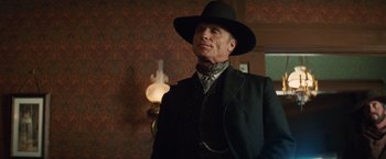 Movie still from “Appaloosa” (2008), directed by Ed Harris – A man wearing a black hat and a black suit; Medium shot, Low angle