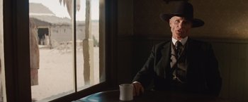 Movie still from “Appaloosa” (2008), directed by Ed Harris – An old man sitting at a table with a cup of coffee; Medium shot, Low angle