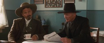 Movie still from “Appaloosa” (2008), directed by Ed Harris – Two men sitting at a table reading a newspaper; Medium shot, Low angle