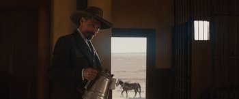 Movie still from “Appaloosa” (2008), directed by Ed Harris – A man holding a coffee pot while standing in front of an open window; Medium shot, Over the shoulder angle