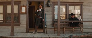 Movie still from “Appaloosa” (2008), directed by Ed Harris – A man standing in front of a wooden building; Wide shot, Low angle
