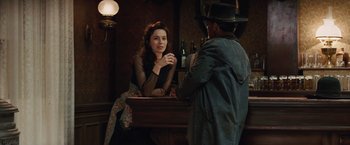 Movie still from “Appaloosa” (2008), directed by Ed Harris – A woman sitting at a table talking to a man in a hat; Medium shot, Over the shoulder angle