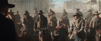 Movie still from “Appaloosa” (2008), directed by Ed Harris – A group of men riding horses down a street; Wide shot, Low angle