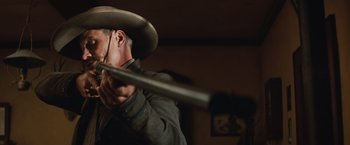 Movie still from “Appaloosa” (2008), directed by Ed Harris – A man in a cowboy hat holding a baseball bat; Close Up shot, Low angle