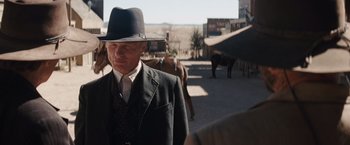 Movie still from “Appaloosa” (2008), directed by Ed Harris – An older man in a suit and hat walking down the street; Medium shot, Over the shoulder angle