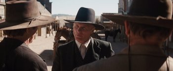 Movie still from “Appaloosa” (2008), directed by Ed Harris – A man wearing a suit and a black hat standing next to a horse; Close Up shot, Over the shoulder angle