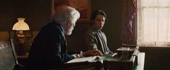 Movie still from “Appaloosa” (2008), directed by Ed Harris – Two men sitting at a table looking at papers; Medium shot, Over the shoulder angle