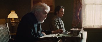 Movie still from “Appaloosa” (2008), directed by Ed Harris – Two people sitting at a table with papers; Medium shot, Over the shoulder angle