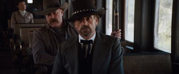 Movie still from “Appaloosa” (2008), directed by Ed Harris – A man in a suit and a cowboy hat; Medium shot, Over the shoulder angle