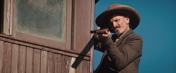 Movie still from “Appaloosa” (2008), directed by Ed Harris – A man with a hat on holding a gun; Medium shot, Low angle