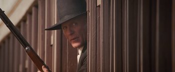 Movie still from “Appaloosa” (2008), directed by Ed Harris – A man wearing a black hat looking out of a window; Close Up shot, Low angle