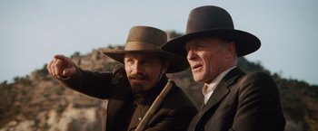 Movie still from “Appaloosa” (2008), directed by Ed Harris – A couple of men standing next to each other on top of a hill; Close Up shot, Low angle