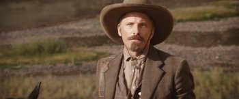 Movie still from “Appaloosa” (2008), directed by Ed Harris – A man with a long beard wearing a cowboy hat; Close Up shot, Over the shoulder angle