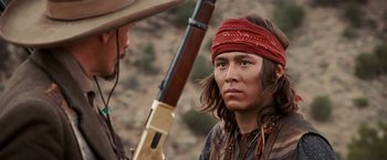 Movie still from “Appaloosa” (2008), directed by Ed Harris – A man with a red bandanna on his head and holding a rifle; Close Up shot, Over the shoulder angle