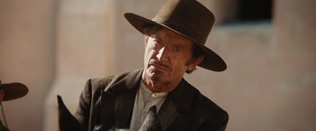 Movie still from “Appaloosa” (2008), directed by Ed Harris – An old man wearing a brown hat and a brown jacket; Close Up shot, Over the shoulder angle